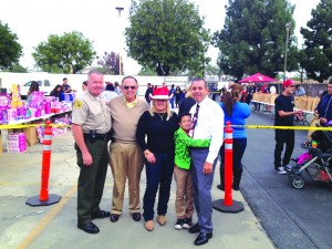 HELPING OUT: From left to right: Norwalk Sheriff's Commander Pat Maxwell, Norwalk Councilman Luigi Vernola, founder of the Santa's Sleigh Foundation, former Pico Rivera Mayor Gracie Gallegos, and newly elected State Senator Tony Mendoza with his son Antonio, Jr. In the background is the donated toy station and the hundreds of bags of food for families in need. Photo by Brian Hews.