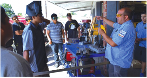 Norwalk High School collision repair instructor Ken Cook (right) explains how to use a miter saw, including safety protocols, to his students.   